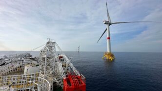 Vista de turbinas eólicas marinas desde barco con grúa. Cables para eólica marina, inversión sostenible en energía renovable y futuro energético.