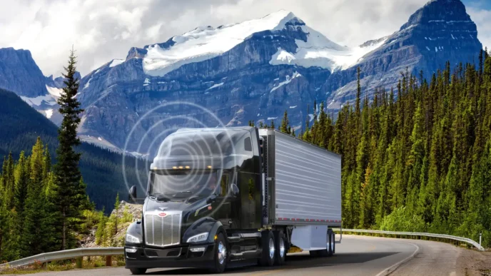 Camión Peterbilt negro en carretera escénica de montaña. Innovación y sostenibilidad en camiones pesados.