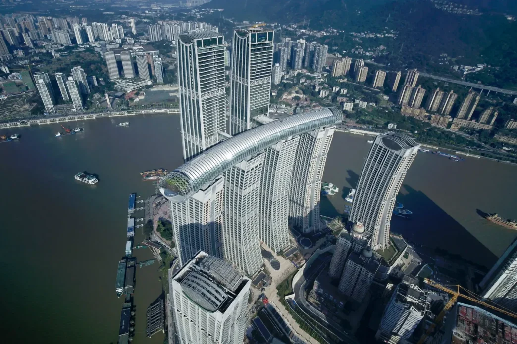 Vista aérea de Raffles City Chongqing, ejemplo de innovación HVAC en desarrollo eco-lujo. Diseño arquitectónico único con rascacielos interconectados.