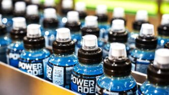 Línea aséptica PET: botellas de Powerade en fila, listas para el embotellado sostenible. Innovación en bebidas deportivas con envases optimizados.