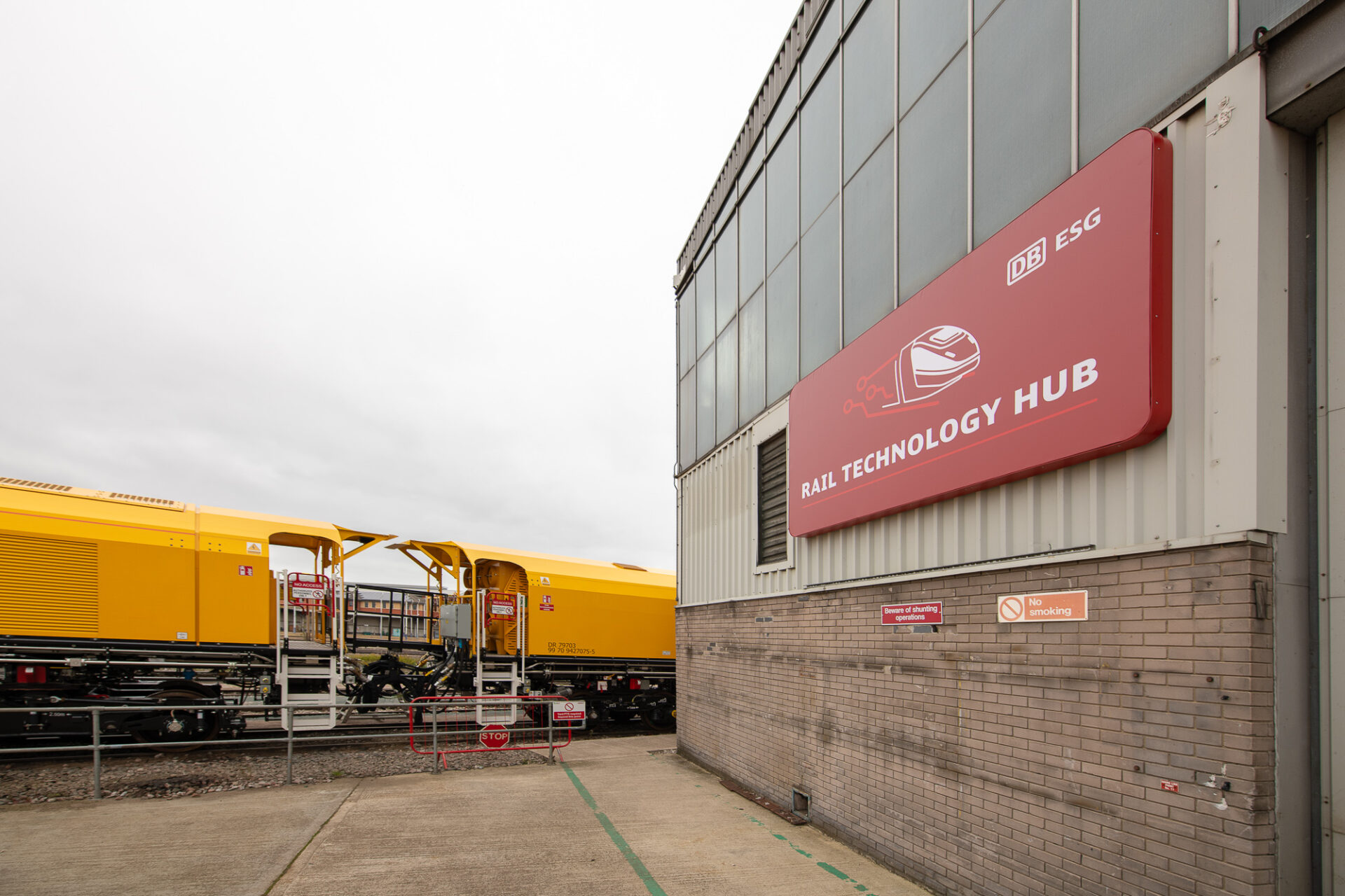 Vista del Rail Technology Hub de Derby, mostrando innovación y sostenibilidad con un tren amarillo de DB ESG en primer plano. Nuevo centro ferroviario.