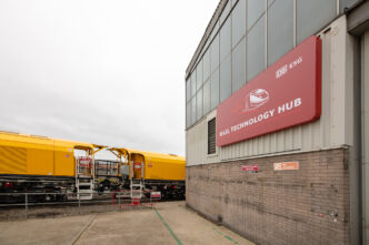 Vista del Rail Technology Hub de Derby, mostrando innovación y sostenibilidad con un tren amarillo de DB ESG en primer plano. Nuevo centro ferroviario.
