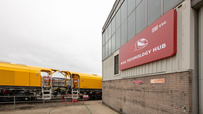 Vista del Rail Technology Hub de Derby, mostrando innovación y sostenibilidad con un tren amarillo de DB ESG en primer plano. Nuevo centro ferroviario.