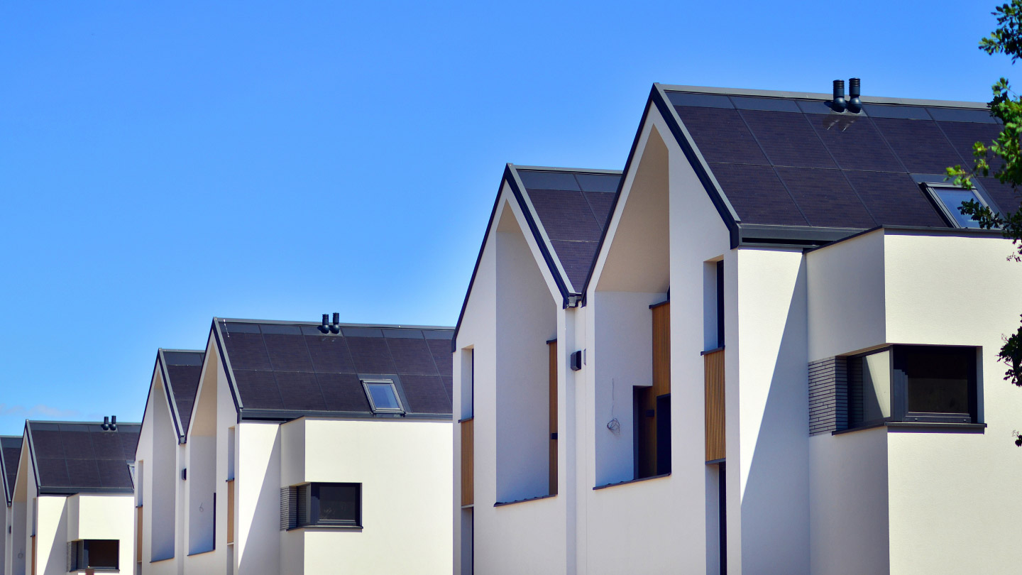 Hilera de casas modernas con paneles solares, reflejando innovación y sostenibilidad en el sector inmobiliario. Impulso al Real Estate 2025.