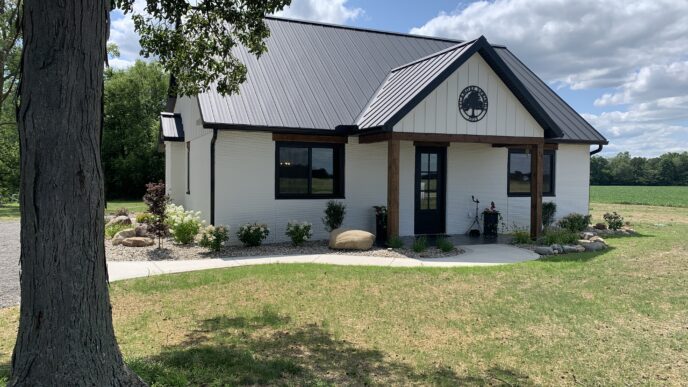 Vivienda 3D innovadora en Ohio. Diseño moderno y sostenible con fachada blanca y techo metálico negro. Arquitectura residencial avanzada.