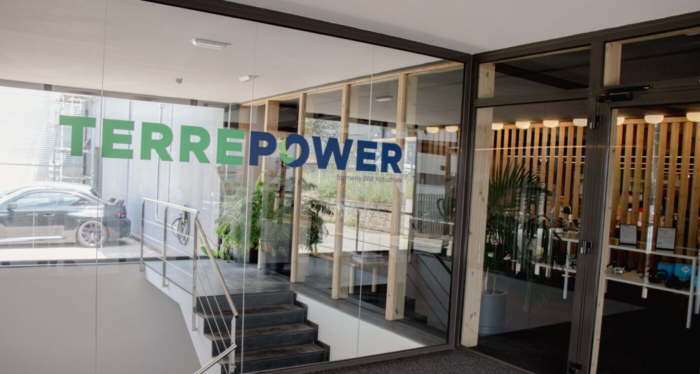 Vista de la entrada de TERREPOWER, mostrando su logo en vidrio y un interior moderno. Innovaciones para un Mercado Sostenible en TERREPOWER.
