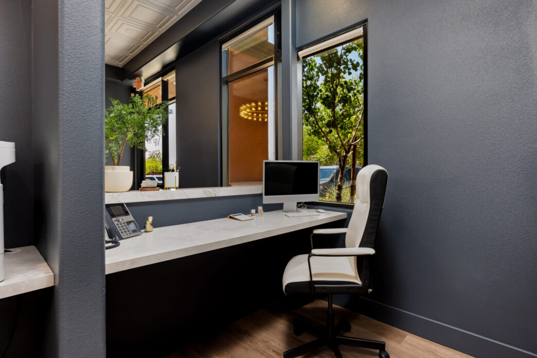 Diseño de interiores comerciales sostenible: Recepción moderna con escritorio de mármol, silla ergonómica y luz natural. Innovación y estilo eco-friendly.