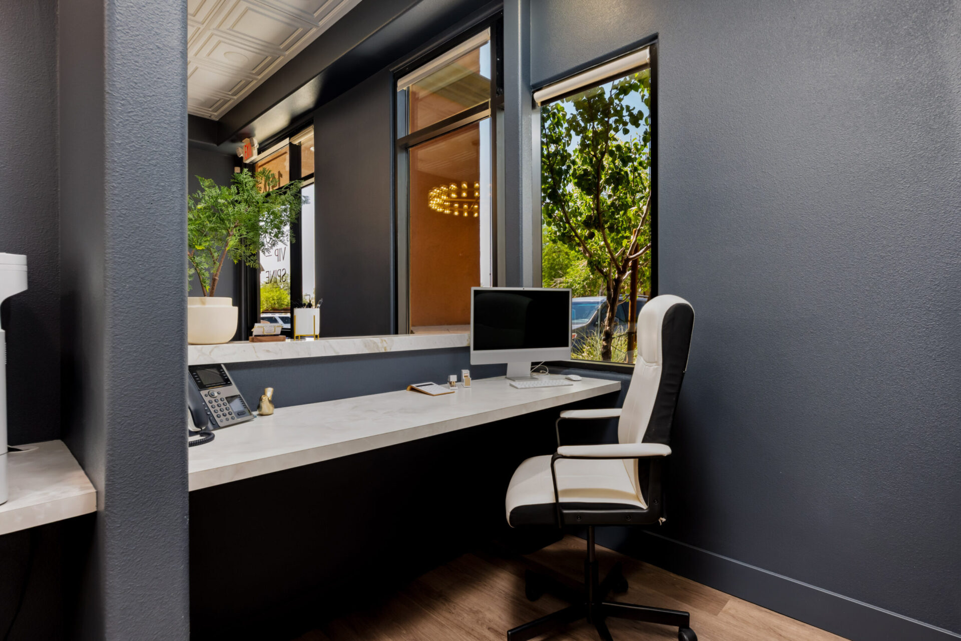 Diseño de interiores comerciales sostenible: Recepción moderna con escritorio de mármol, silla ergonómica y luz natural. Innovación y estilo eco-friendly.