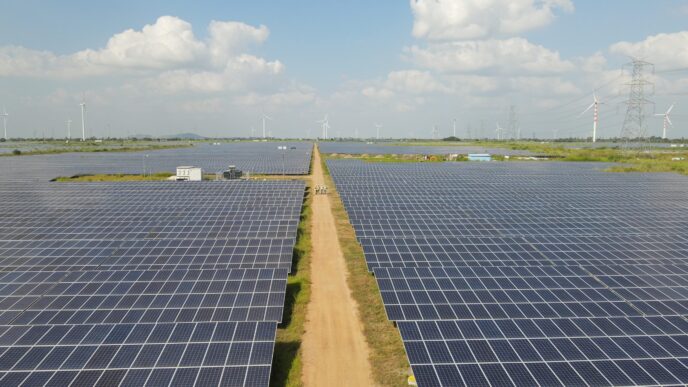 Amplia vista de parque solar con paneles azules y turbinas eólicas al fondo. Inversión en Blueleaf Energy impulsa infraestructura verde. BII.