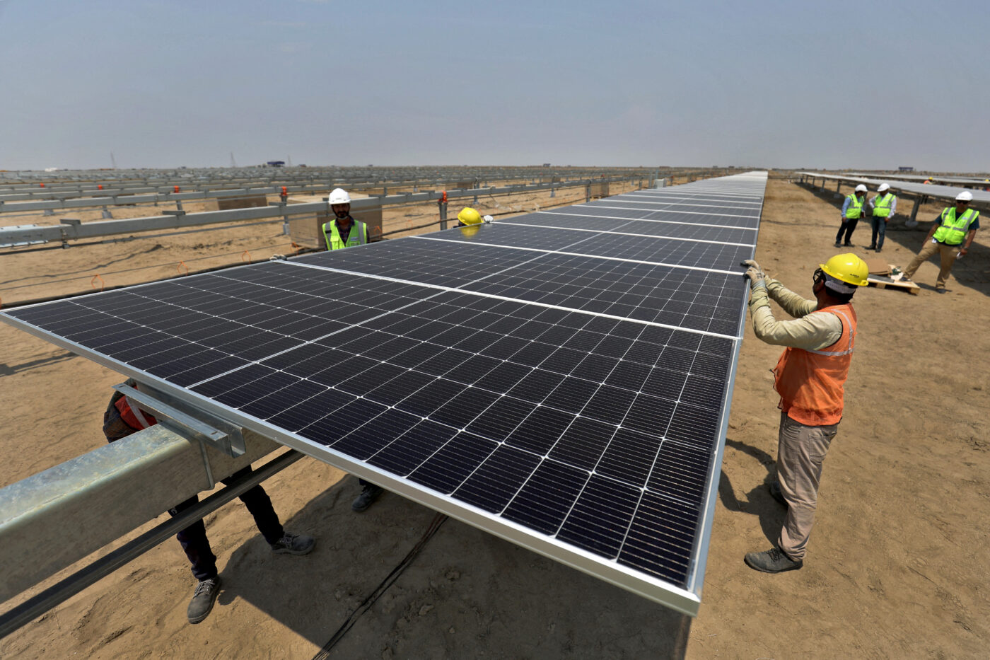 Instalación de paneles solares en India para impulsar la energía limpia. Trabajadores en campo solar, reflejo de la inversión millonaria.
