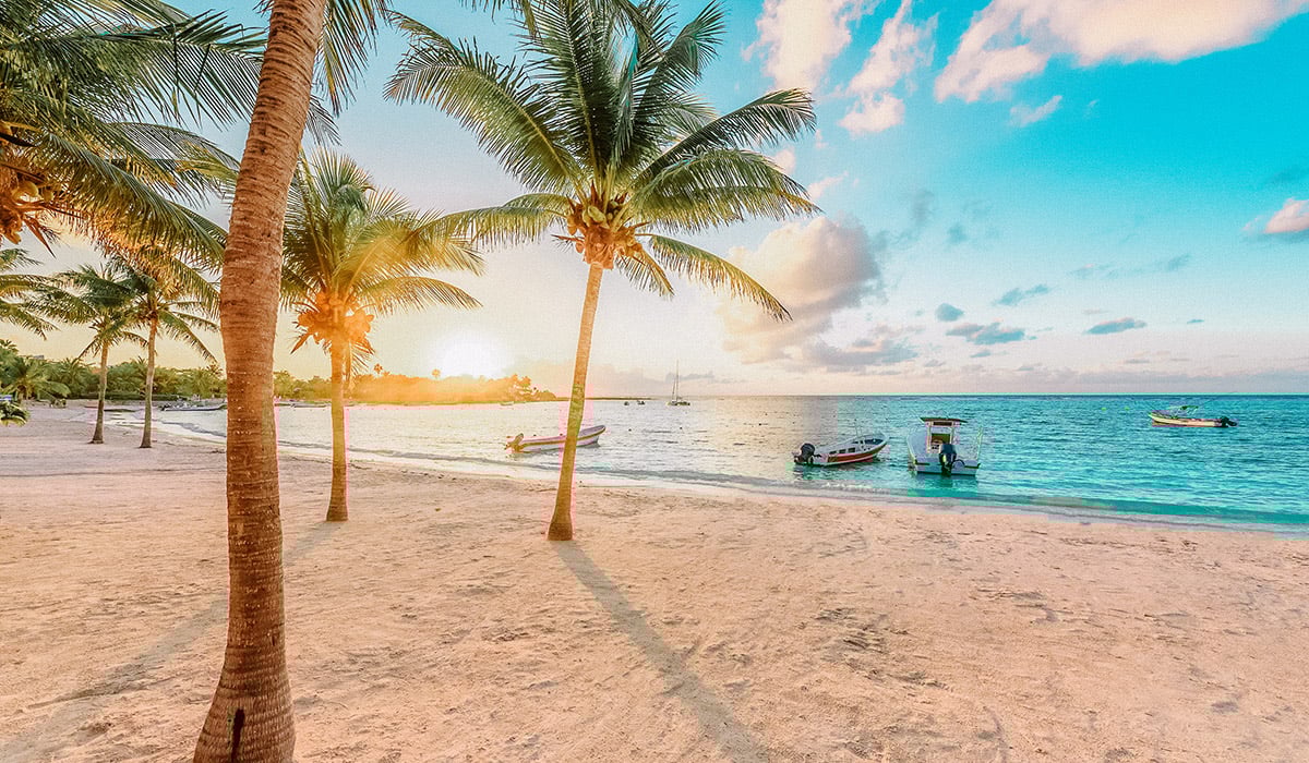 Ciudad de la Riviera Maya, México, sede de Inmobiliare Summits. Playa con palmeras y botes. Destino ideal para invertir en real estate.