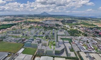 Vista aérea de Meadow at LIMA Estate, Batangas. Inversiones sostenibles, edificios modernos, paisaje urbano y monte en el horizonte.