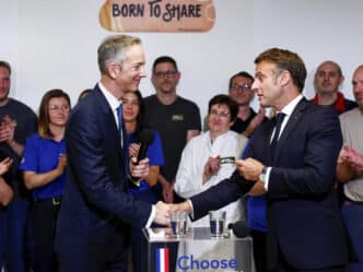 OK. Here's the alt text for the image:

**Speakers/Headshot**

Apertón de manos entre Emmanuel Macron y un orador en evento. El público aplaude. Inmobiliare Summits real estate conference.