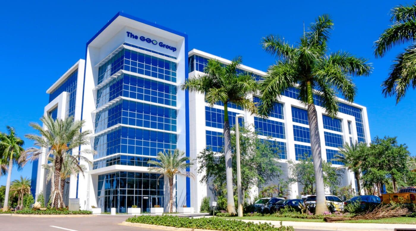 Edificio moderno de oficinas de Javer con fachada de cristal y palmeras, reflejando resultados positivos 3T2023. Arquitectura corporativa y cielo azul.