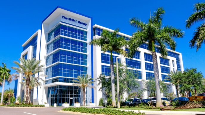 Edificio moderno de oficinas de Javer con fachada de cristal y palmeras, reflejando resultados positivos 3T2023. Arquitectura corporativa y cielo azul.