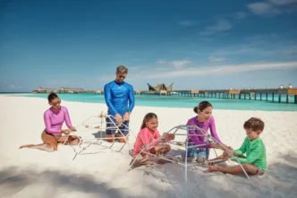 Familia construye estructura en JOALI Maldives, mostrando sostenibilidad y compromiso EarthCheck Gold. Resort paradisíaco con playa y agua turquesa.
