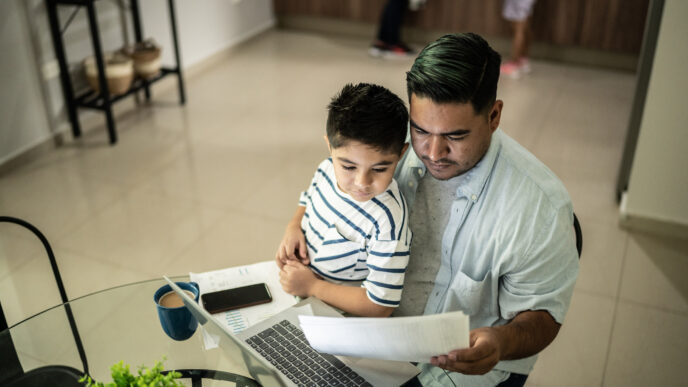 Joven mexicano con hijo revisando documentos en laptop, analizando opciones para adquirir o rentar vivienda. Retos de vivienda para jóvenes en México.