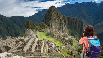 Turista capturando la majestuosidad de Machu Picchu, impulso al turismo en Nuevo León. Montañas imponentes y ruinas antiguas en un paisaje andino único.