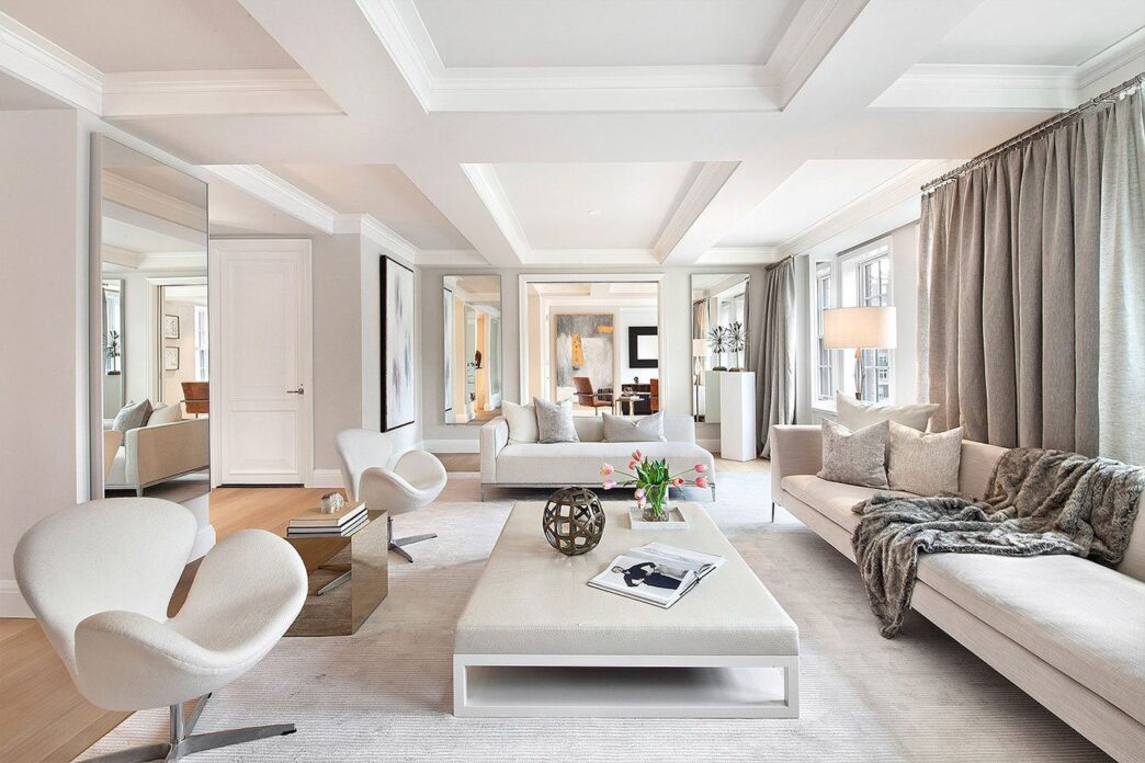 Interior de sala de estar de lujo. Sofás claros, sillas de diseño y espejos amplían el espacio. Arquitectura del lujo en real estate con luz natural.