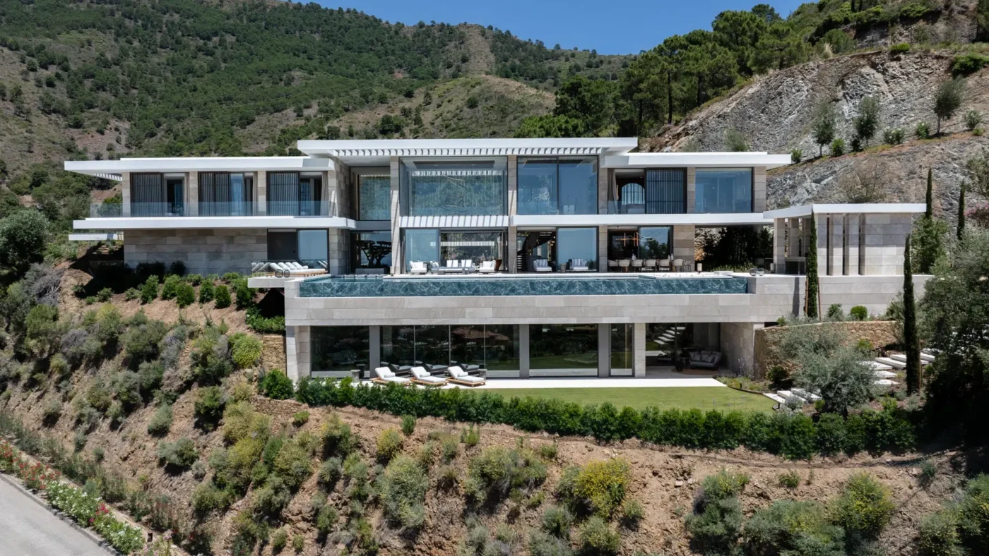 Arquitectura moderna en Marbella: Villa de lujo con piscina infinita que redefine el horizonte, integrándose en la ladera con vistas panorámicas.
