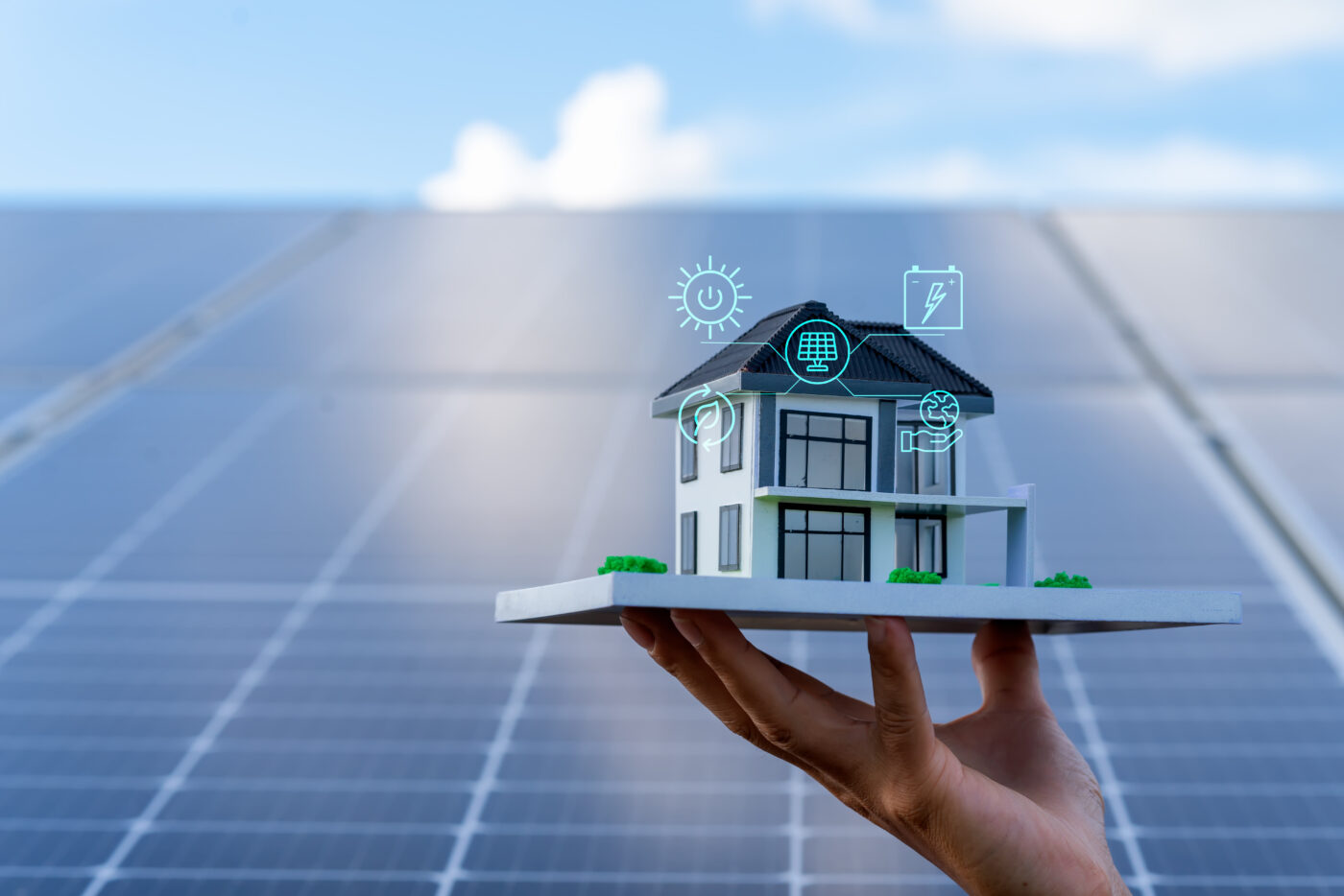 Mano sosteniendo maqueta de casa con paneles solares, simbolizando la eficiencia energética en el sector inmobiliario. Energía sostenible, eco-hogar.