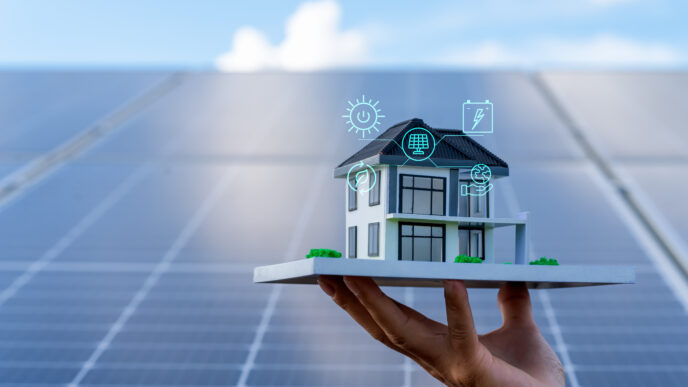Mano sosteniendo maqueta de casa con paneles solares, simbolizando la eficiencia energética en el sector inmobiliario. Energía sostenible, eco-hogar.