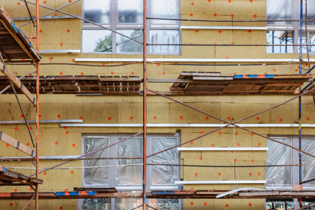 Fachada con aislamiento térmico, andamio. Eficiencia energética en construcción europea moderna, reduciendo consumo y mejorando sostenibilidad.