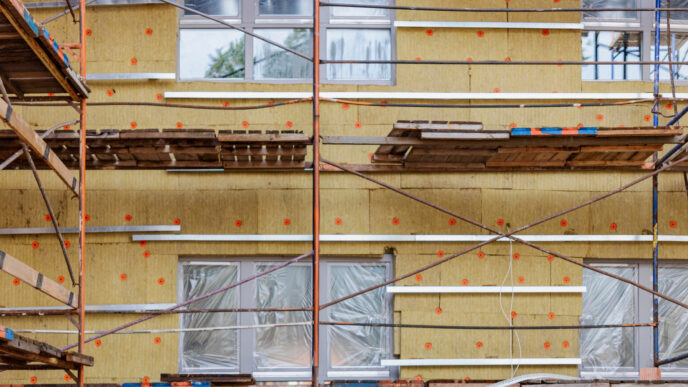 Fachada con aislamiento térmico, andamio. Eficiencia energética en construcción europea moderna, reduciendo consumo y mejorando sostenibilidad.