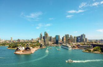 Vista aérea de Sídney, Australia, mostrando la Ópera, el puerto con barcos y el perfil urbano. Mercado inmobiliario de lujo australiano.