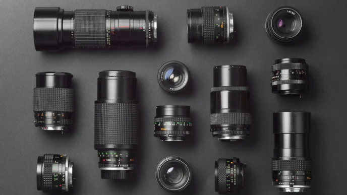 Variedad de lentes industriales negros sobre fondo oscuro. Selección de lentes para visión artificial y sistemas de inspección industrial.