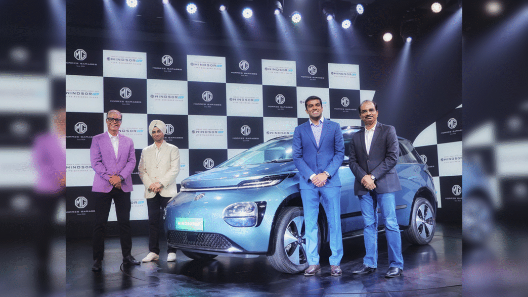 Presentación de MG con movilidad eléctrica e impacto BaaS en real estate. Cuatro personas posan frente a un coche azul eléctrico en un evento.