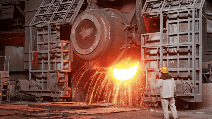 Trabajador supervisa la colada de acero fundido en una fábrica, destacando la revolución del acero verde en el sector inmobiliario APAC.