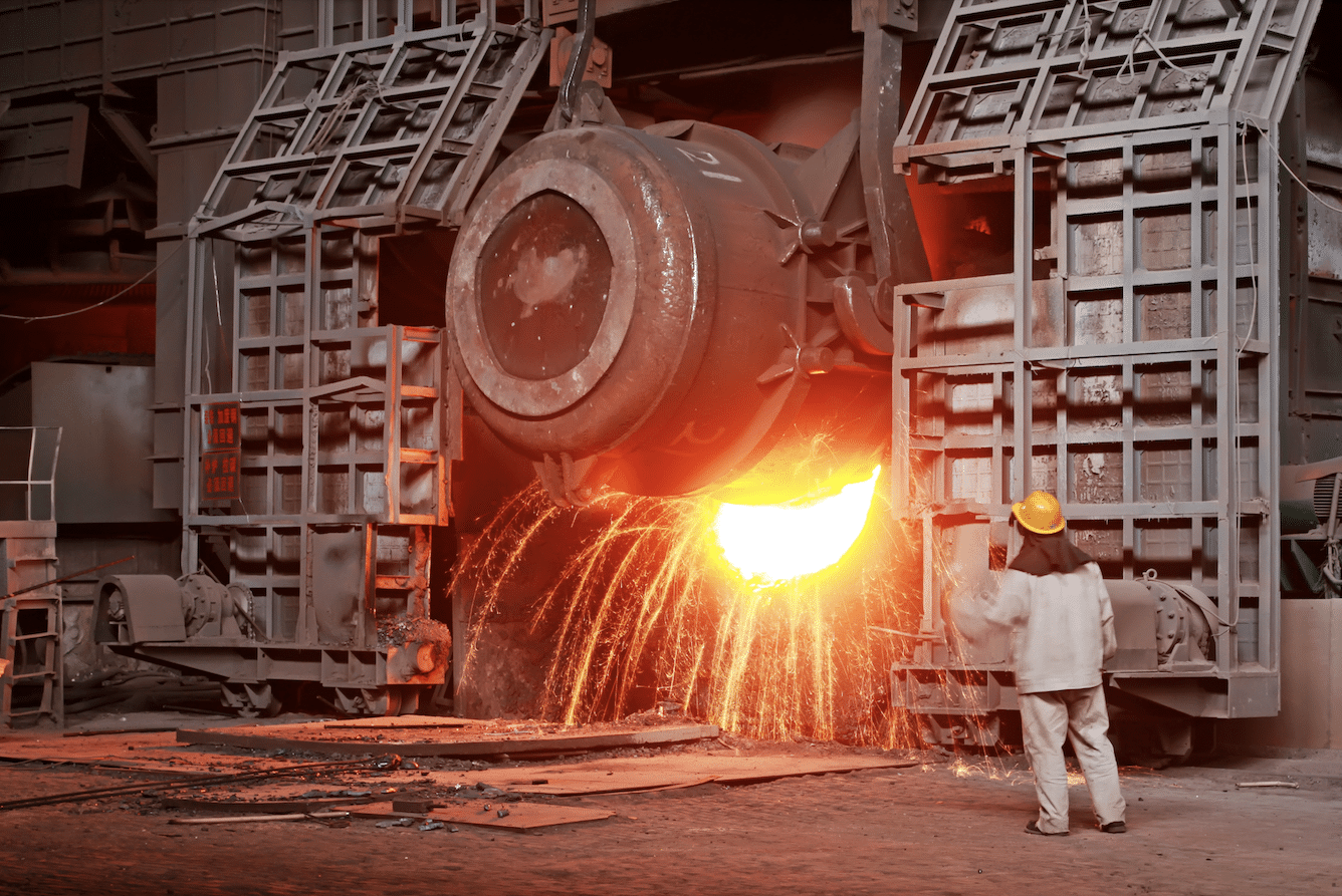 Trabajador supervisa la colada de acero fundido en una fábrica, destacando la revolución del acero verde en el sector inmobiliario APAC.