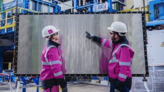 Dos ingenieros examinan panel de hidrógeno en Alemania. Revolución del hidrógeno en real estate alemán. Cascos blancos y chaquetas rosas. Innovación.
