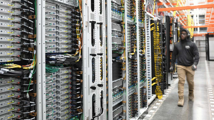 Centro de datos Google: filas de servidores con cables y técnico trabajando, representando la transición energética en la infraestructura digital.