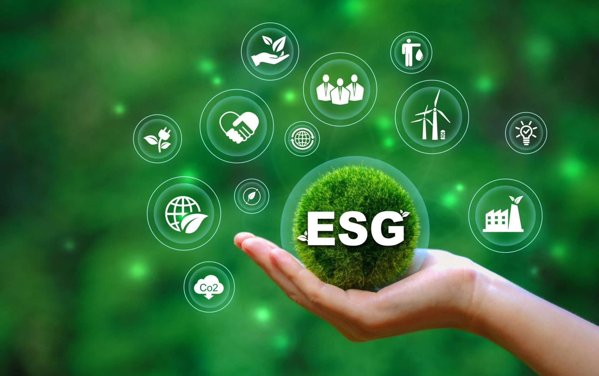 Mano sosteniendo esfera de musgo con 'ESG' y íconos, simbolizando liderazgo ESG en inversiones inmobiliarias, seguridad y sostenibilidad.