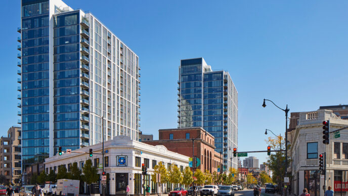 Desarrollo BTR Naperville por Lincoln Property Co.: Dos torres modernas dominan el paisaje urbano, con tráfico y peatones en una calle arbolada.