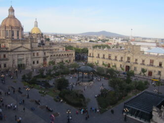 Vista elevada de la Plaza Guadalajara con edificios históricos. Locales en transición a oficinas de gobierno. Arquitectura y actividad urbana visible.