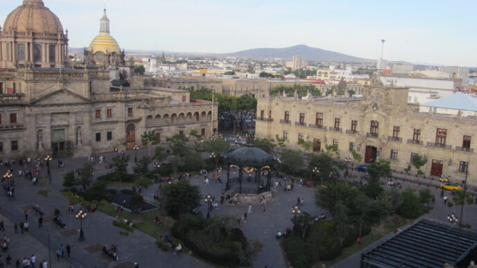 Vista elevada de la Plaza Guadalajara con edificios históricos. Locales en transición a oficinas de gobierno. Arquitectura y actividad urbana visible.