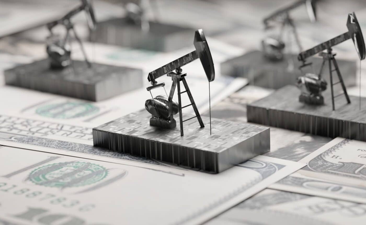 Concepto de energía en Inmobiliare Summits. Modelos de torres de perforación petrolera sobre billetes de dólar. Riesgos de inversión en LATAM.