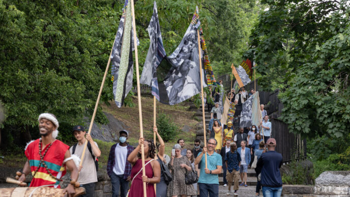 Celebración cultural con música y banderas en evento artístico. Grupo subiendo escaleras, ambiente festivo. Evento de Bellas Artes.