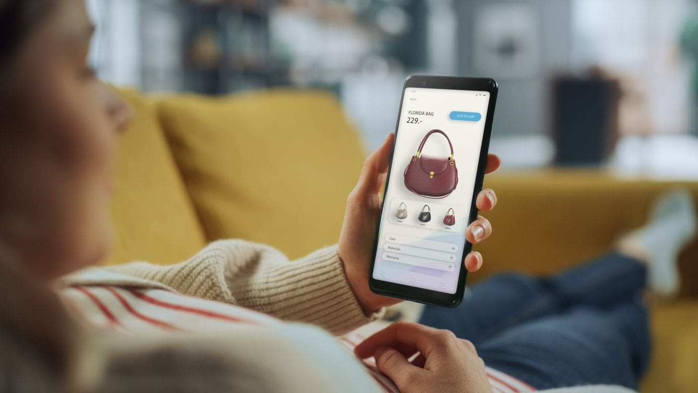 Compras online en México: Mujer mira bolso en app de e-commerce en su móvil. El sector de real estate se adapta al comercio digital.