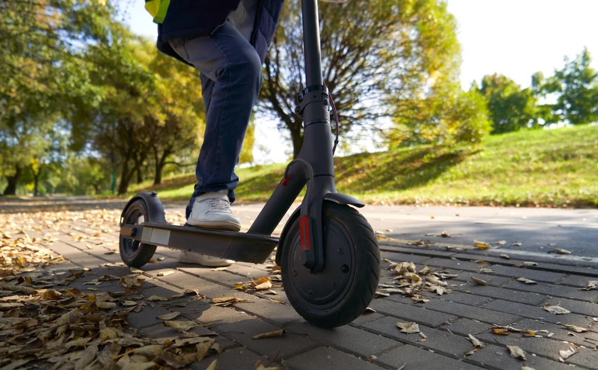 city/destination
Micromovilidad urbana: persona en patinete eléctrico en calle arbolada. Movilidad sostenible en Inmobiliare Summits, LATAM.
