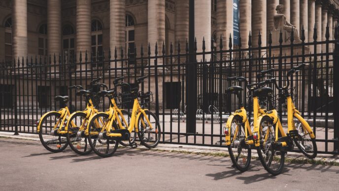 Movilidad Sostenible en Bucarest: Bicicletas amarillas 'Little Bolt' estacionadas frente a edificio histórico. Alternativa ecológica y moderna.
