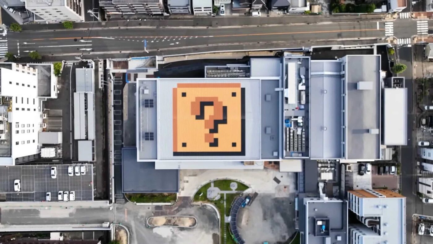 Vista aérea del futuro Museo de Nintendo en Japón, con un bloque de interrogación gigante en el techo. Apertura en marzo de 2024. Edificios y ciudad.