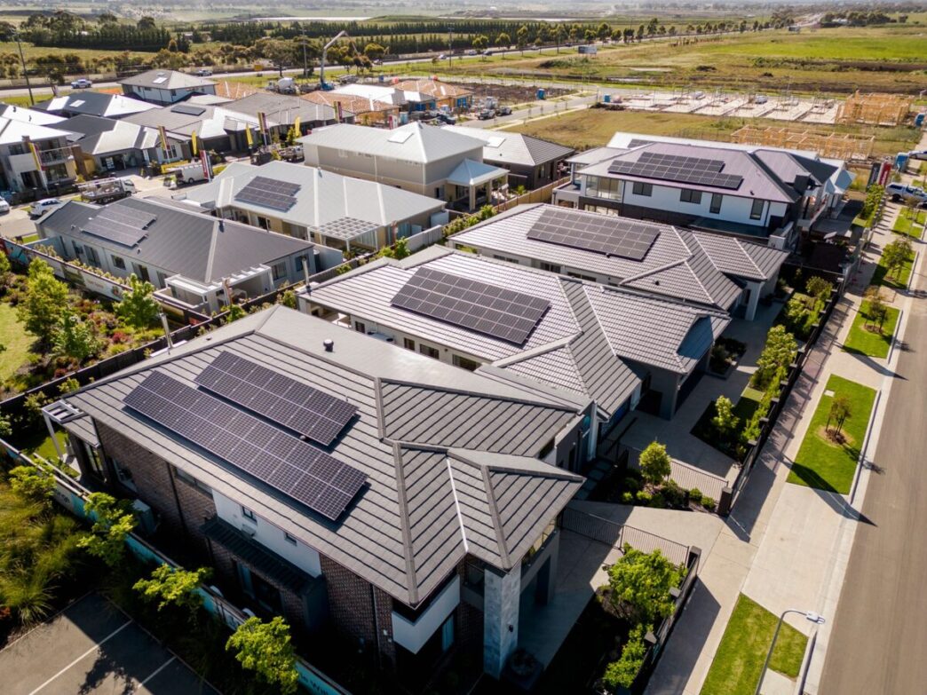 Vista aérea de casas con paneles solares en Nueva Zelanda. Instalaciones solares aceleradas gracias a exenciones regulatorias, reflejando energía limpia.