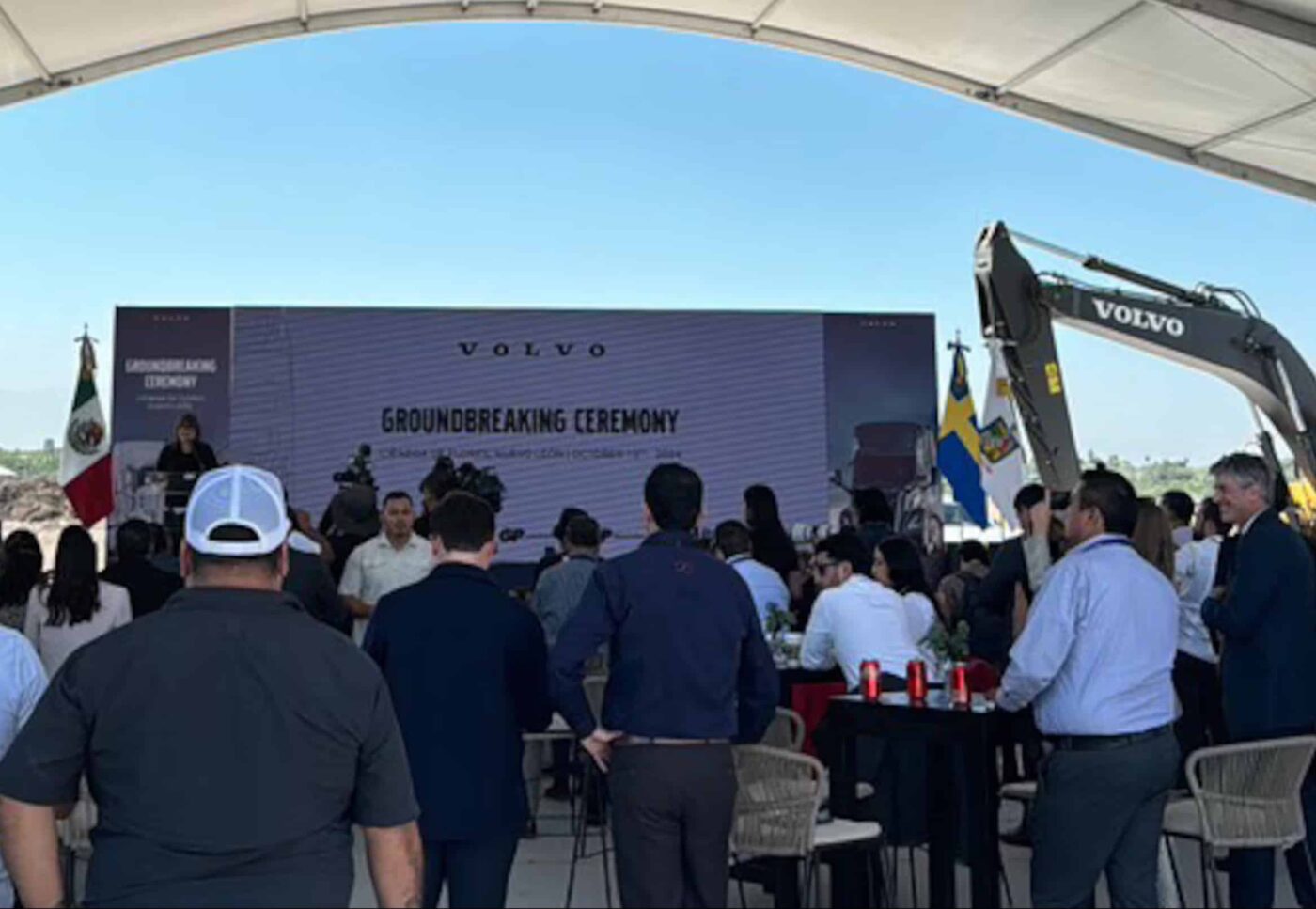 Inauguración planta Volvo Nuevo León: Asistentes observan el evento de inicio de construcción con maquinaria Volvo y banderas de México y Suecia.