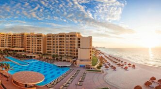 Vista aérea de hotel de lujo en México con piscina y playa. Anticipa ocupación del 68.1% en fin de semana largo de noviembre. ¡Reserva ahora!
