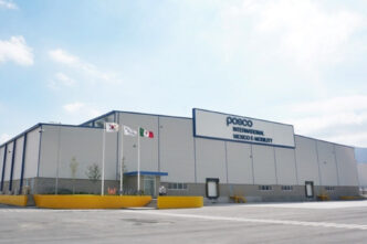 Planta industrial de POSCO International en Coahuila. Edificio moderno con banderas de Corea, México y el logo de POSCO. Inauguración de fábrica.