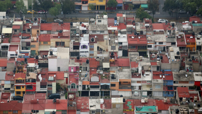 Vista aérea de viviendas en México con techos rojos. Refleja el aumento en el precio de la vivienda desde la pandemia. Arquitectura urbana densa.